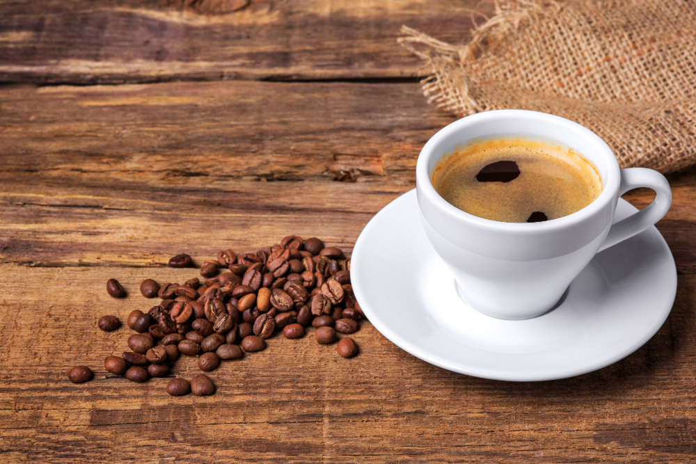 Quais são os melhores horários para tomar café? 4 xicara de cafe em uma mesa de madeira parede escura